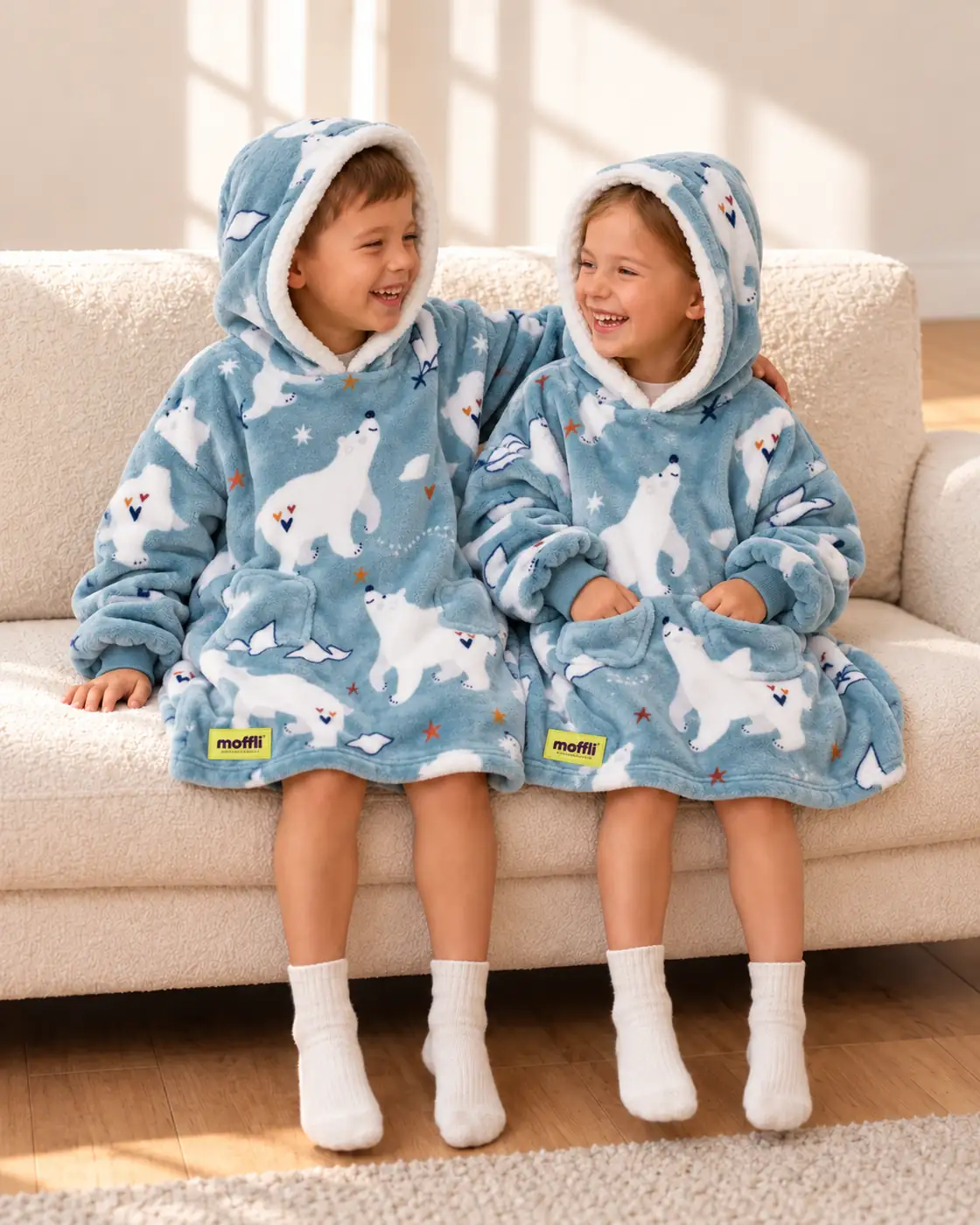 Boy and girl sitting on the sofa wearing the Polar Bear Kids Moffli and hood up