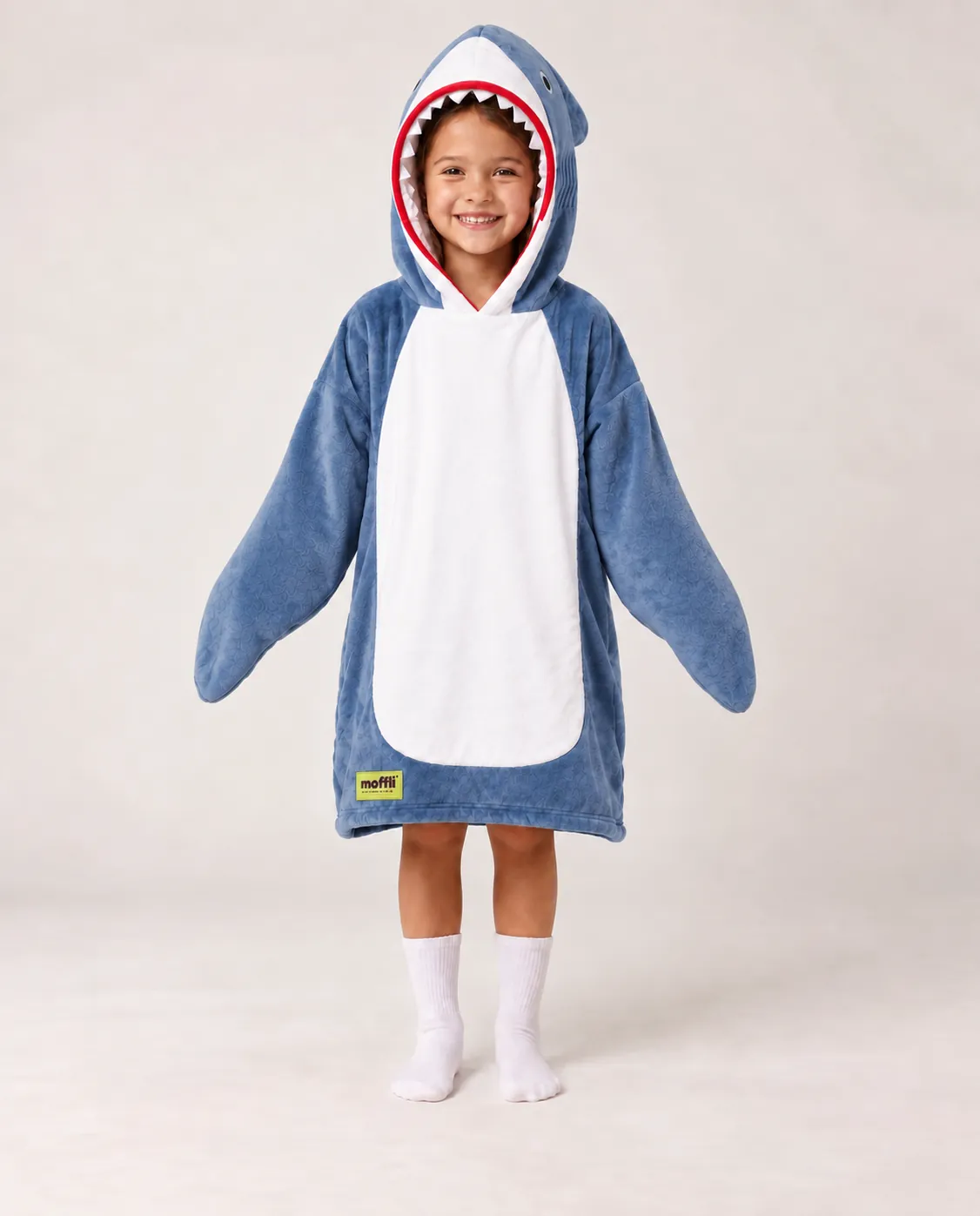 Girl standing wearing the Shark Kids Moffli and the shark hood up, open sleeves and Moffli label
