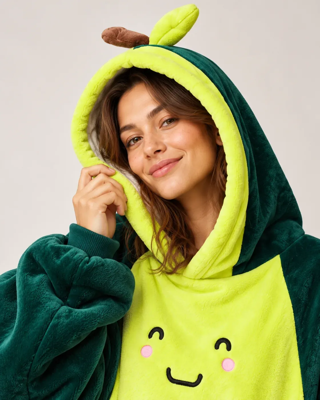 Close-up of a smiling woman wearing the Avocado Moffli hood, with leaf and stem