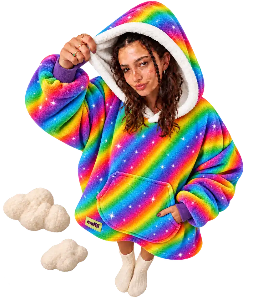 Model seen from above wearing the Moffli with rainbow stripes and stars, hand lifting the white-lined hood, other hand in the pocket, Moffli label and two soft clouds