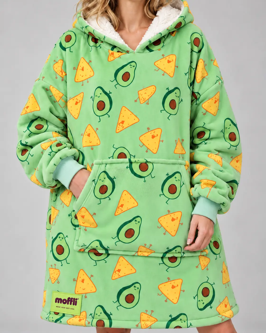 Smiling woman with the white-lined hood of the Avocado & Nachos Moffli and hands in pocket