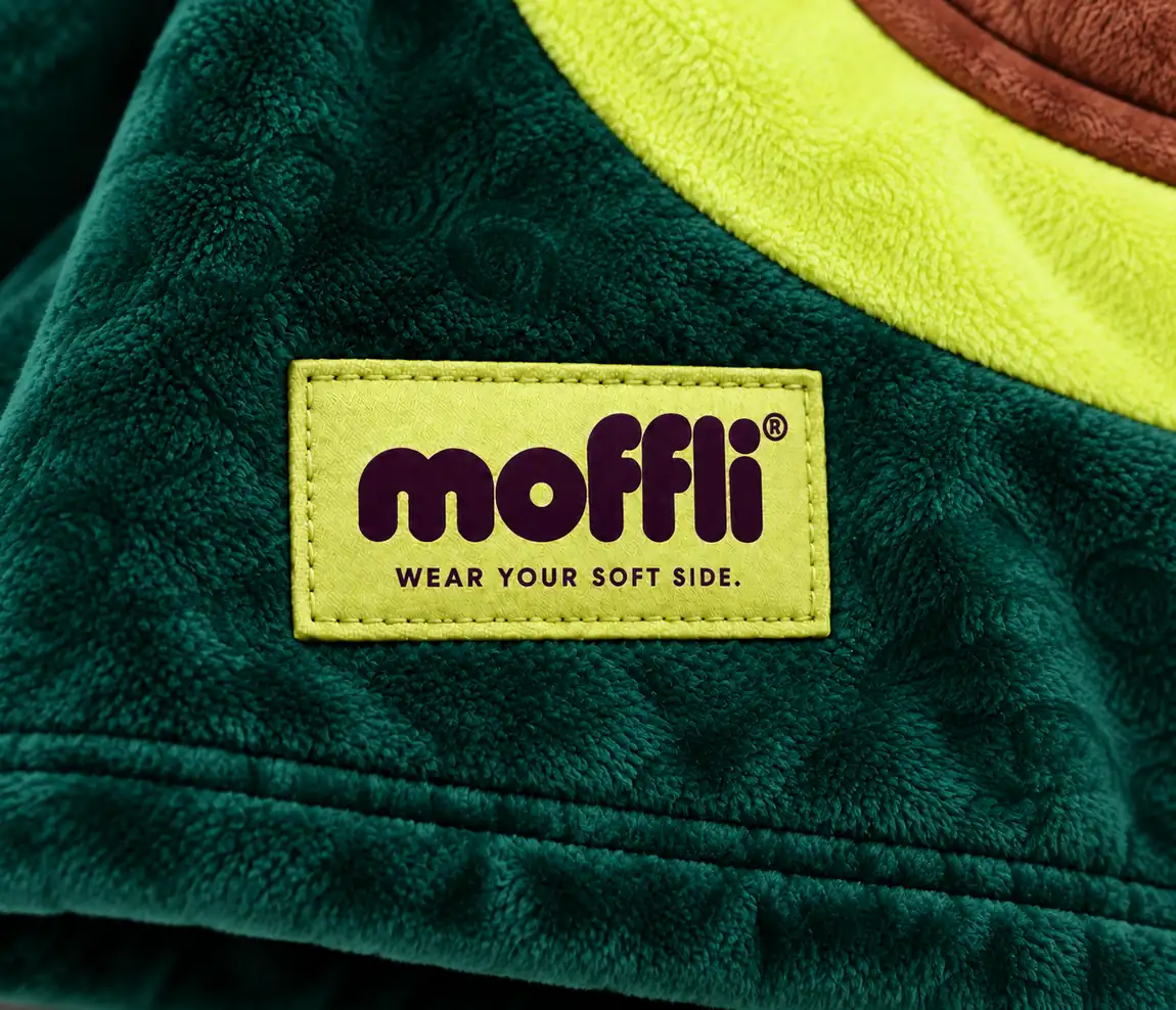 Close-up of the dark green fleece of the Avocado Kids Moffli with lime panel, brown pocket and Moffli "Wear your soft side" label