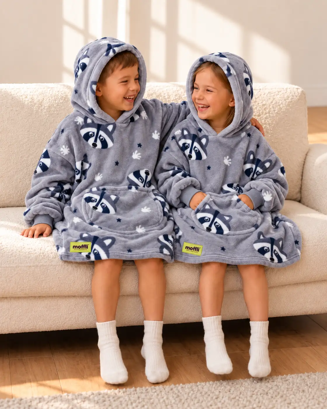 Boy and girl sitting on the sofa wearing the Raccoon Kids Moffli and hood up