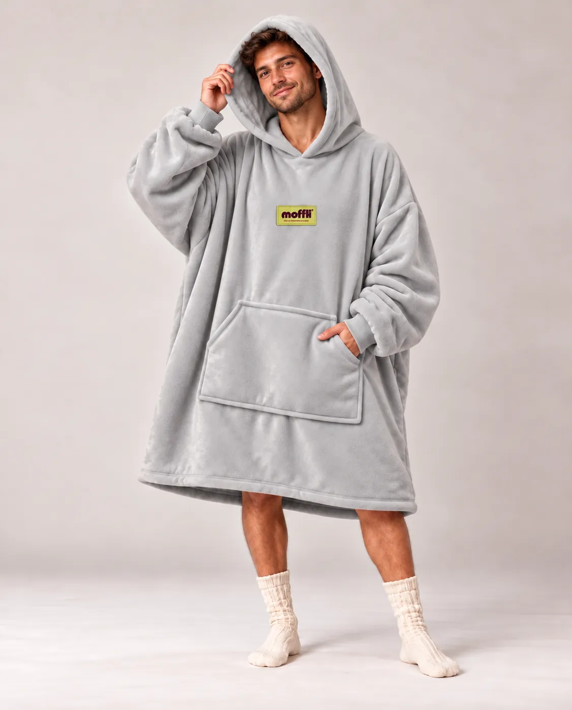 Smiling man with the Cloud Grey Moffli, hood up and one hand in the kangaroo pocket