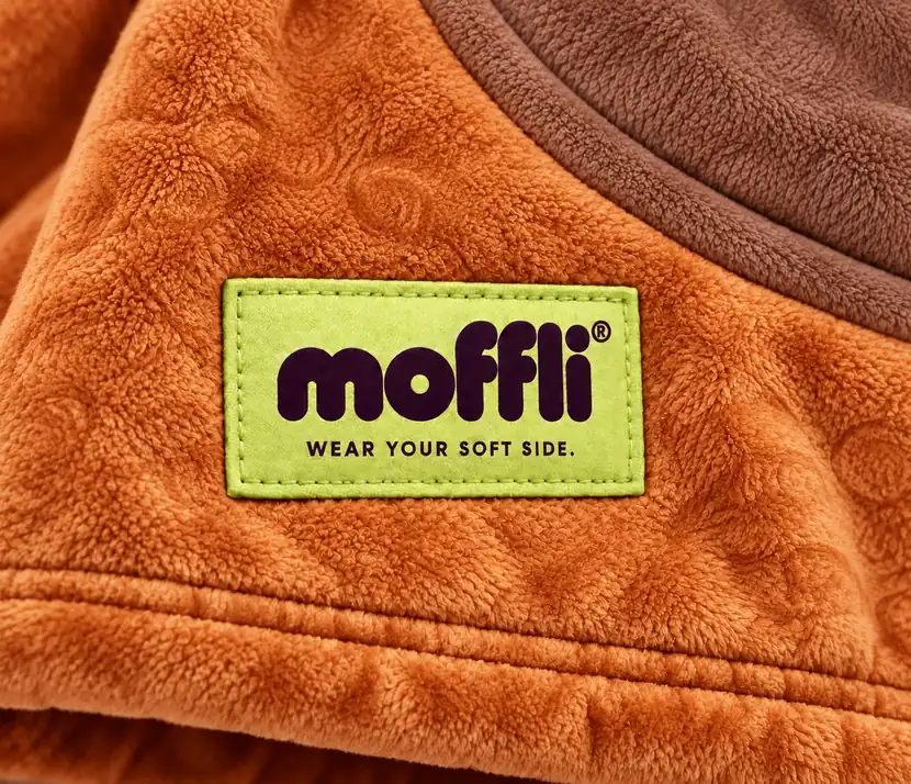 Close-up of the pistachio Moffli "Wear your soft side." label on the orange Capybara fabric