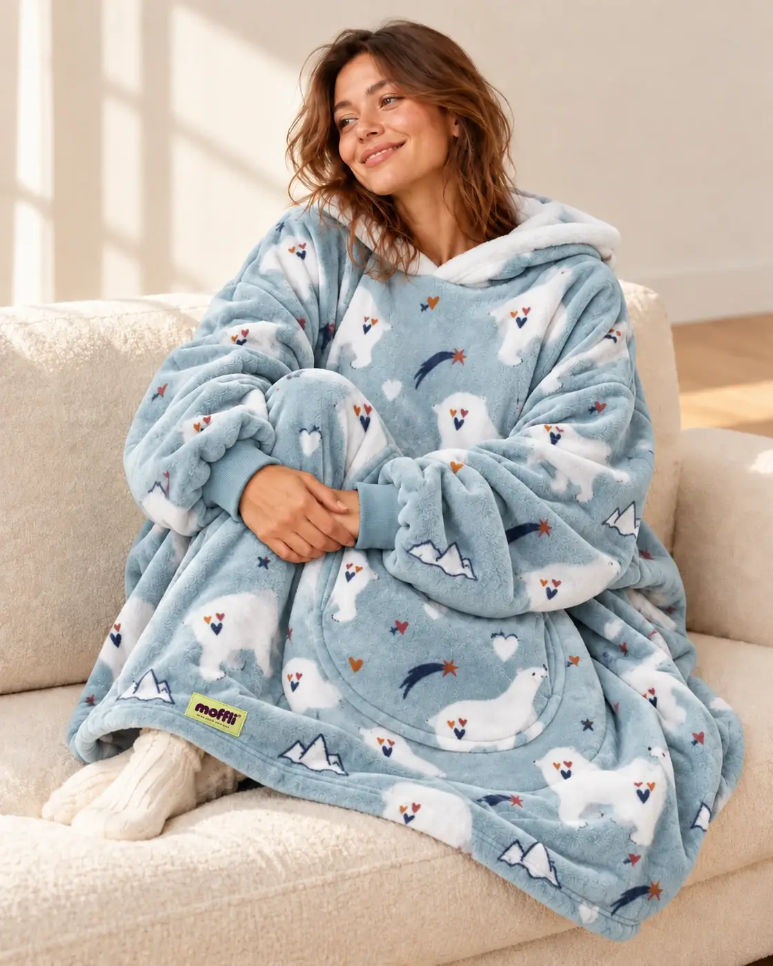 Woman sitting on the sofa wrapped in the blue Polar Bear Moffli