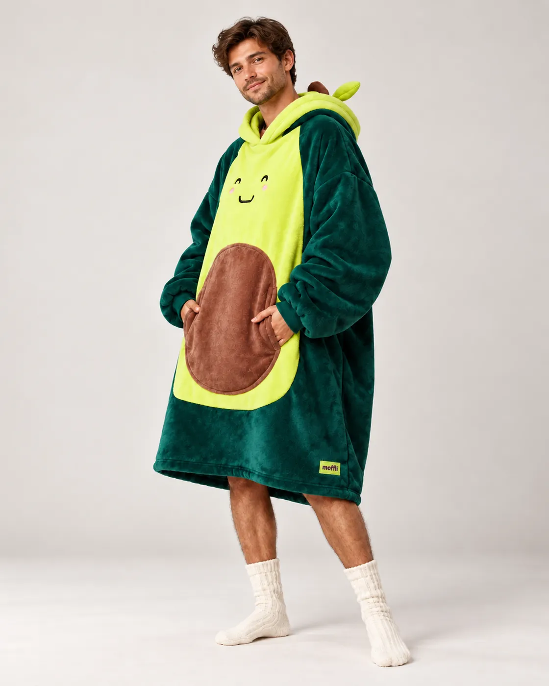 Smiling man full length wearing the green Avocado Moffli, hands in the pit pocket and white knee-high socks