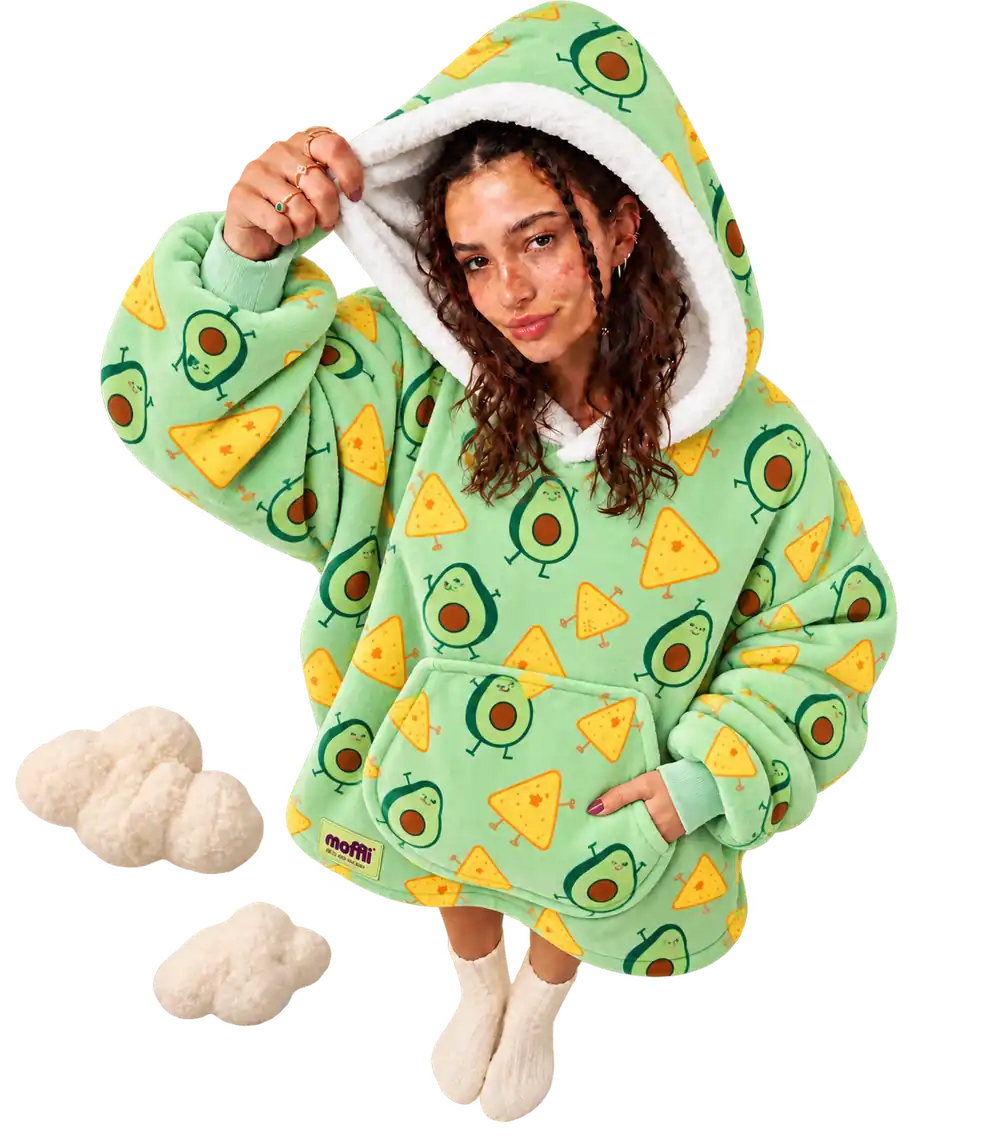 Model seen from above wearing the green Moffli with avocado and nachos print, hand lifting the white-lined hood, other hand in the pocket, Moffli label and two soft clouds