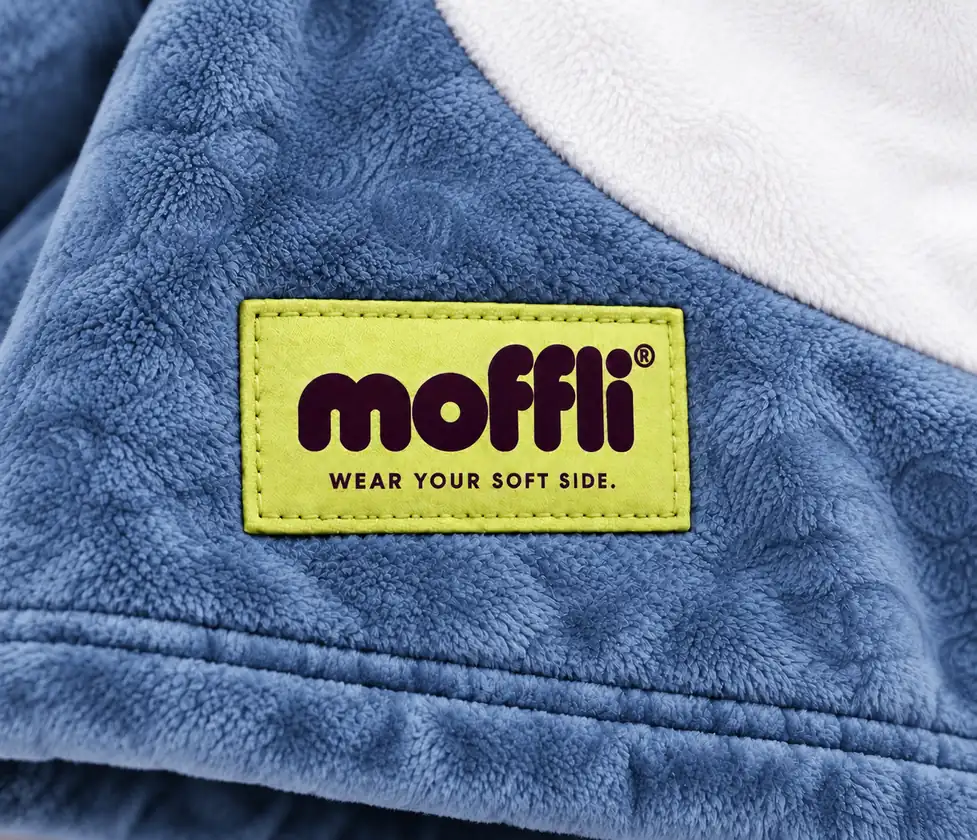 Close-up of the blue fleece of the Shark Kids Moffli with white panel and Moffli "Wear your soft side" label